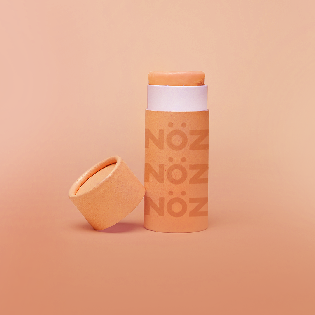 Reef safe, cruelty-free neon orange Nöz sunscreen in a orange background