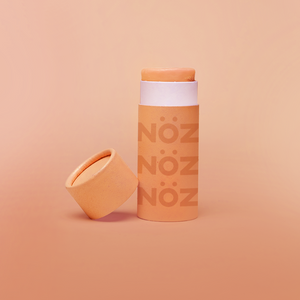 Reef safe, cruelty-free neon orange Nöz sunscreen in a orange background